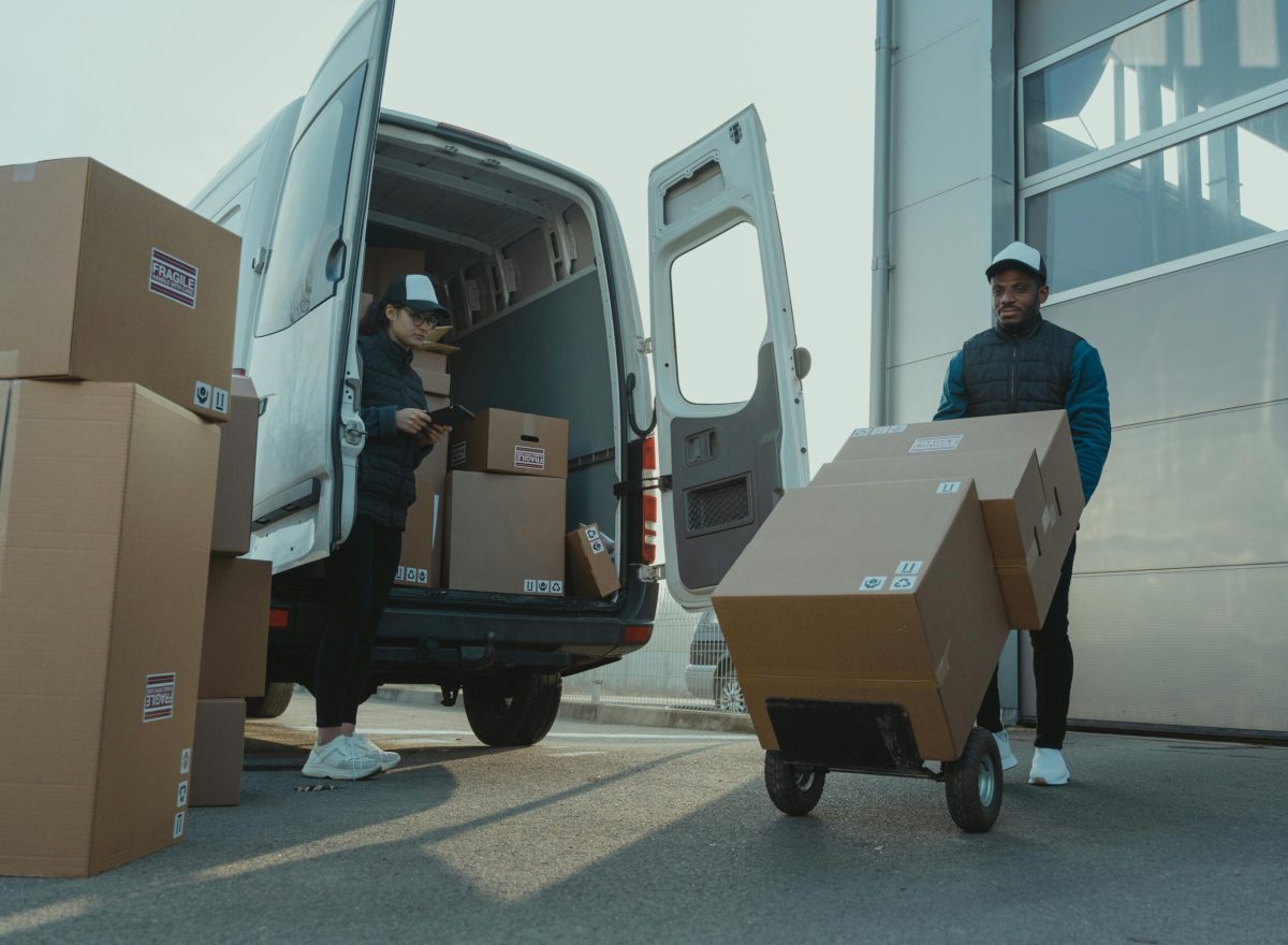 Two couriers load boxes into a van for shipment, showcasing logistics and teamwork.